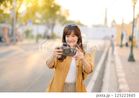 Traveler asian woman in her 30s using smartphone to take a photo while traveling urban street in Bangkok, Thailand Traveler asian woman in her 30s using smartphone to take a photo while traveling urban street in Bangkok, Thailand 125221685
