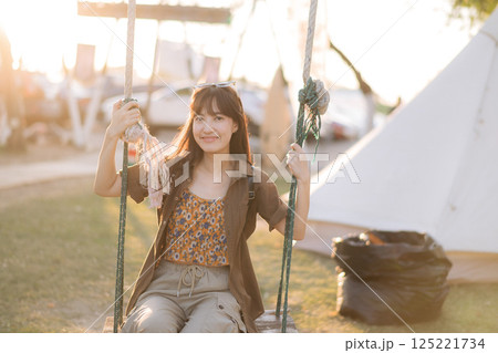asian woman sitting in swing at camping site. 125221734