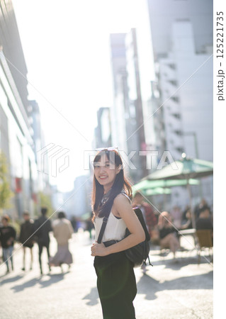 City vibes in Tokyo, a smiling woman in a white shirt, adding vibrancy to the dynamic urban landscape. 125221735
