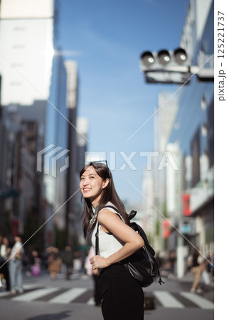 Tokyo vibes, A confident Japanese woman in her 30s, blending business, technology, and urban style while enjoying a leisurely walk. 125221737