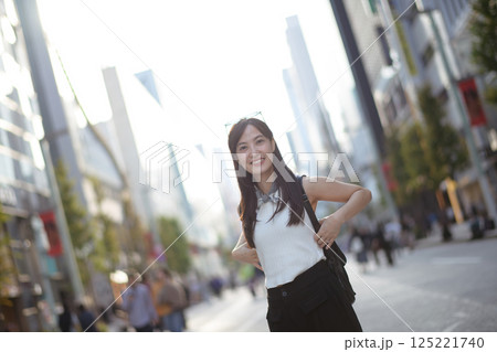 A portrait of urban bliss, a young, confident Asian woman exudes positivity, style, and a carefree attitude in the cityscape. A portrait of urban bliss, a young, confident Asian woman exudes positivity, style, and a carefree attitude in the cityscape. 125221740