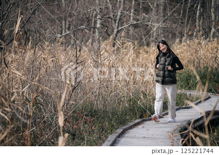 Adventure in Japan, An Asian woman explores a hiking route, captivated by the stunning fall colors under the silver sky. 125221744
