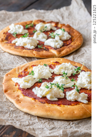 Mini pizzas baked with tomato sauce, stracciatella cheese, and fresh thyme garnish 125221825