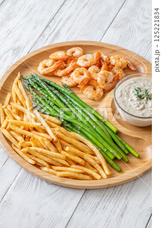 Rustic wooden tray serves full meal of shrimp, asparagus, fries, and sauce Rustic wooden tray serves full meal of shrimp, asparagus, fries, and sauce 125221834