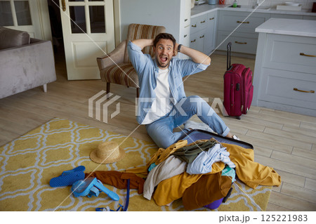 Crazy mad man tourist screaming while sitting front of unpacking travel bag 125221983