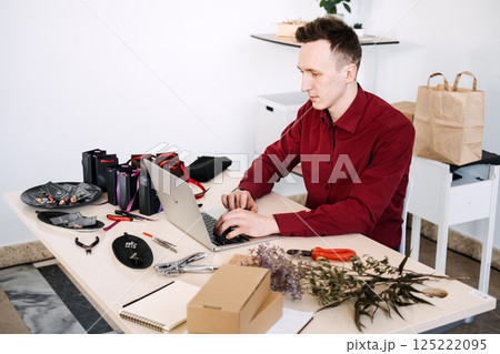 Modern jewelry artisan organizes product logistics and packaging for online sales while working in a minimalist home studio 125222095