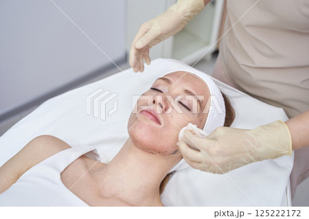 Caucasian female receiving facial treatment in spa setting with gloved hands 125222172