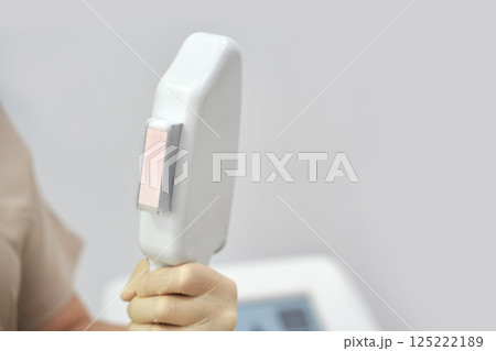Close up of hand holding laser hair removal device in medical setting Close up of hand holding laser hair removal device in medical setting 125222189
