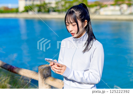 屋外でスマホを持つ女性　驚く　悩む　SNSトラブル 125222392