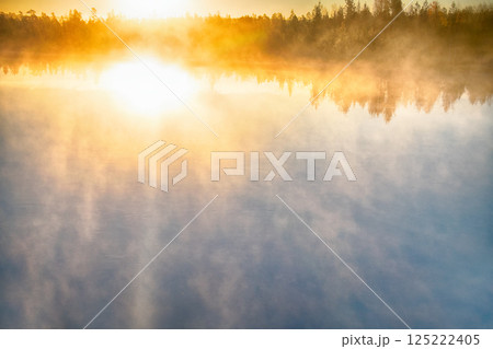 Fog creeps over river on rising sun background Fog creeps over river on rising sun background 125222405