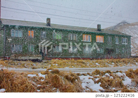 weather it is snowing in evening, house among mountains 125222416