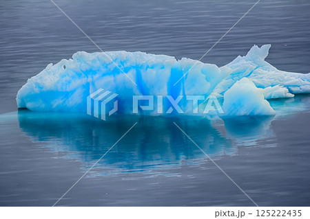 Blue growler (piece of iceberg) with reflection in calm water Blue growler (piece of iceberg) with reflection in calm water 125222435