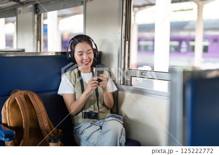 Entertainment and Enjoyment. A young woman listens to music on her phone while traveling on a train. Entertainment and Enjoyment. A young woman listens to music on her phone while traveling on a train. 125222772