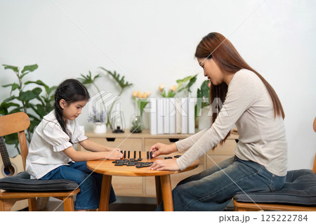 Focused Learning and Play. A mother and daughter enjoy a quiet moment playing a game together. 125222784