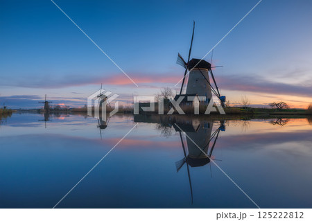 Windmills in the Netherlands during sunset. Historical architecture and buildings. Dutch canals. 125222812