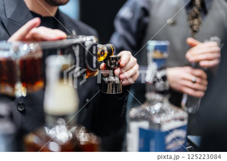 Mixing craft cocktails at a bustling bar downtown in the evening hours 125223084