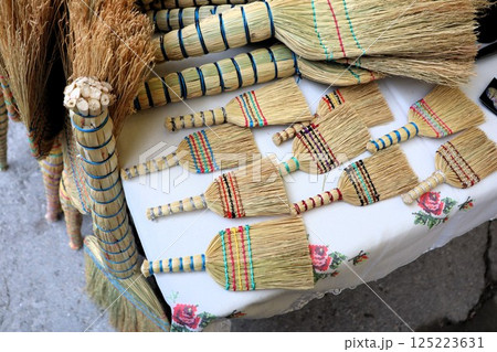 A Collection of Colorful Handcrafted Brooms Beautifully Displayed for Sale at Market 125223631