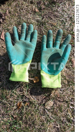 A Pair of Worn Gardening Gloves Laid Out on a Green Grass Surface in the Yard Environment 125223673