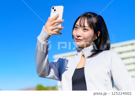 スマホを持つ手で自撮りするかわいい女性　セルフィー　SNS　日常　映え　トリミングアップ 125224002