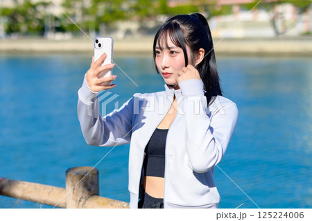 スマホを持つ手で自撮りするかわいい女性　セルフィー　SNS　日常　映え　トリミングアップ 125224006