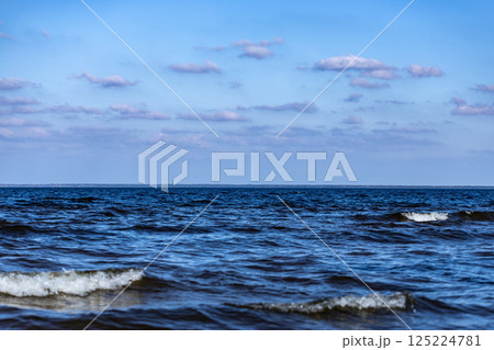 A Serene Seascape: Waves Gently Lapping Against the Shore Under a Clear Blue Sky with Fluffy Clouds, Perfect for Relaxation and Contemplation in Nature's Embrace A Serene Seascape: Waves Gently Lapping Against the Shore Under a Clear Blue Sky with Fluffy Clouds, Perfect for Relaxation and Contemplation in Nature's Embrace 125224781