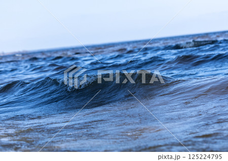 A Serene View of Gentle Ocean Waves Gliding Across the Surface Under a Clear Sky, Capturing the Beauty and Tranquility of the Seaside and Nature's Waterscape 125224795