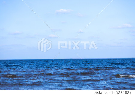 A Tranquil Seascape Featuring Vibrant Blue Waters Under a Clear Sky with Gentle Waves and Floating Clouds, Capturing the Essence of Serene Natural Beauty and Coastal Charm 125224825