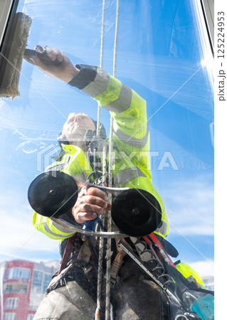 Window Cleaner Performing His Duties on a Bright Sunny Day, Utilizing a Squeegee to Ensure Clear Visibility and Sparkling Surfaces on Tall Urban Buildings Window Cleaner Performing His Duties on a Bright Sunny Day, Utilizing a Squeegee to Ensure Clear Visibility and Sparkling Surfaces on Tall Urban Buildings 125224953