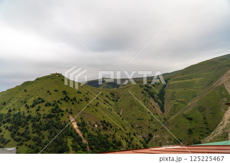 The mountains are covered in lush green trees and the sky is cloudy The mountains are covered in lush green trees and the sky is cloudy 125225467