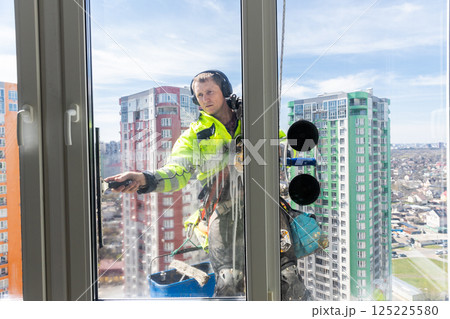 Professional Window Cleaner Works on Skyscraper, Showcasing the Importance of Safety and Precision in High-Rise Building Maintenance and Cleaning Services Professional Window Cleaner Works on Skyscraper, Showcasing the Importance of Safety and Precision in High-Rise Building Maintenance and Cleaning Services 125225580
