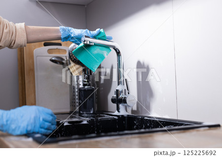 A Close-Up of a Person Cleaning the Kitchen Sink with a Cotton Cloth, Demonstrating Home Maintenance and Hygiene Practices for a Sparkling Clean Surface 125225692