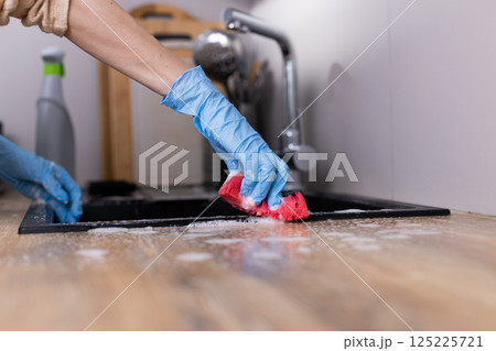 Person Cleaning Kitchen Counter with Sponge and Gloves - Maintaining a Tidy Home and Hygiene with Effective Cleaning Methods for a Healthy Living Environment 125225721