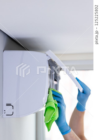 Effective Cleaning of Air Conditioning Unit by a Person in Gloves for Optimal Performance and Hygiene, Ensuring Fresh Air Quality in Indoor Spaces for Better Comfort 125225802