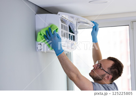 Professional Air Conditioner Cleaning and Maintenance by a Skilled Technician in a Modern Indoor Environment with Emphasis on Hygiene and Efficiency 125225805