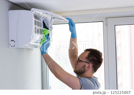 Expert Maintenance on Air Conditioning Unit: A Professional Cleans and Maintains HVAC System for Optimal Performance and Air Quality Management in a Modern Space 125225807