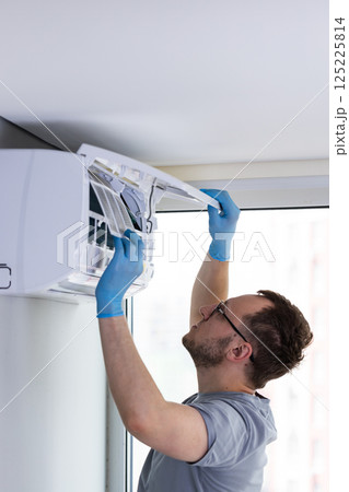 Professional Technician Performing Maintenance on Air Conditioning Unit: Importance of Regular Servicing for Optimal Performance and Efficiency in Modern Indoor Environments 125225814