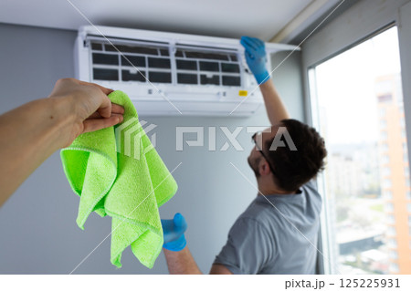 Cleaning and Maintenance of an Air Conditioning Unit by a Professional, Demonstrating Proper Techniques for Hygiene and Efficiency in Home Cooling Systems 125225931