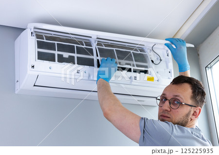 Professional HVAC Technician Performing Maintenance on Air Conditioner Unit Inside a Modern Room for Improved Indoor Air Quality and Efficiency in Home Cooling Solutions 125225935