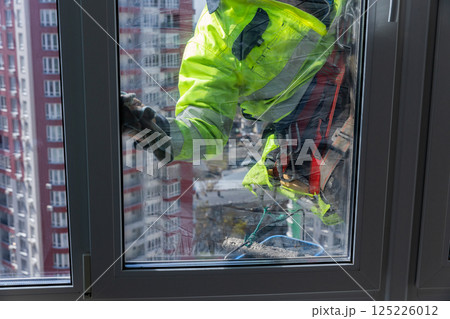 Window Cleaning Professional Maintaining Bright and Clear Panes on a Tall Building in a Vibrant Cityscape with Reflective Glass and a Diligent Worker in Safety Gear 125226012