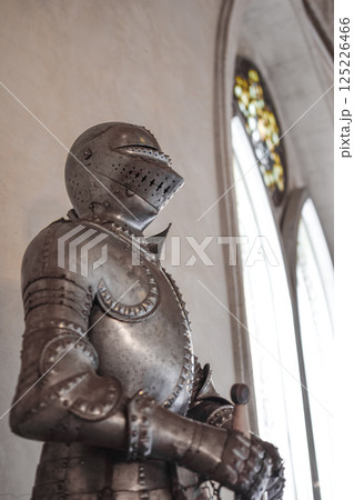 Side view of Medieval shiny armor and gothic pointed arches in white background 125226466