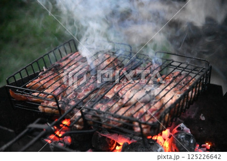 Grilled meat steak on stainless grill depot with flames on dark background. Food and cuisine 125226642