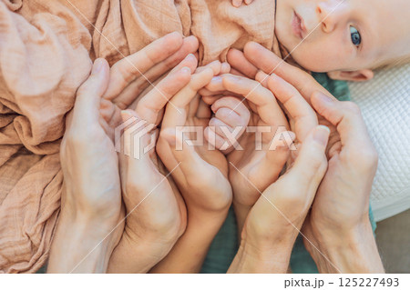 Newborn tiny hand surrounded by family. Symbol of love, protection, and strong family bonds. Parenthood, childhood, and unconditional love concept 125227493