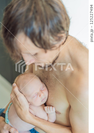 Father cuddling his sleeping newborn son skin-to-skin. Tender parental bonding and newborn care. Fatherhood, love, and early parent-child connection concept 125227494