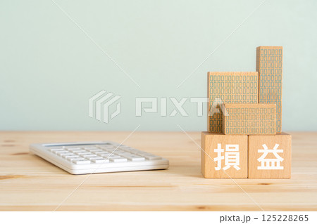 損益と書かれたブロック、電卓、不動産の模型 125228265