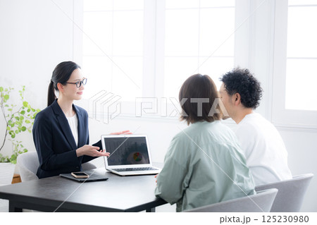 生命保険やローンの相談などを夫婦と営業マンの女性 125230980