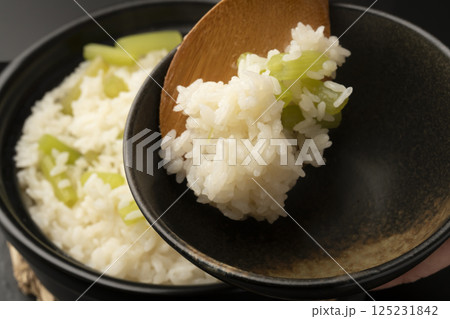 土鍋で炊いたふきの炊き込み御飯を茶碗に盛り付ける 125231842