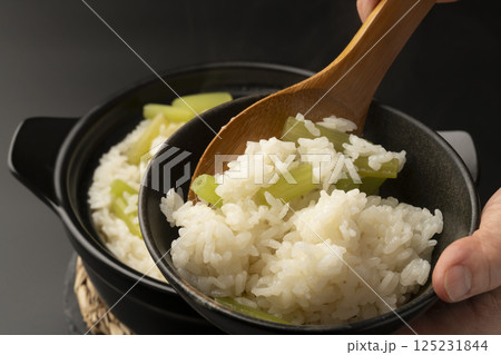 土鍋で炊いたふきの炊き込み御飯を茶碗に盛り付ける 土鍋で炊いたふきの炊き込み御飯を茶碗に盛り付ける 125231844