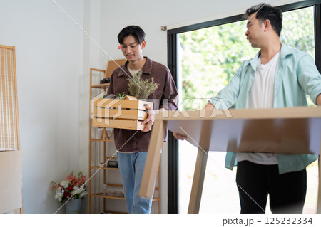 LGBTQ couple happily moving furniture into their new home, showcasing love and partnership. 125232334