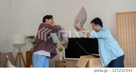 Gay couple having fun throwing pillows during their move. 125232342