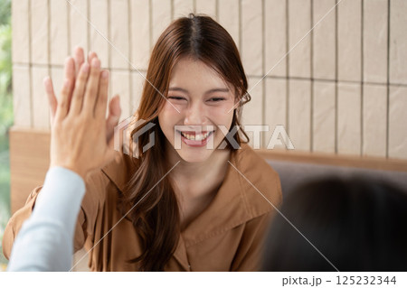Teamwork and Encouragement. A student sharing a high-five with her friend in a lively study moment. Teamwork and Encouragement. A student sharing a high-five with her friend in a lively study moment. 125232344